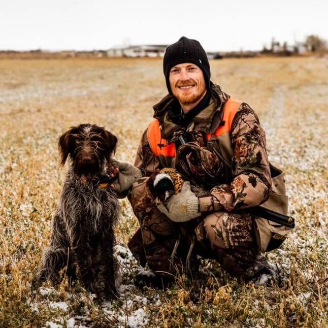 Wirehaired Pointing Griffon with handler and retrieved pheasant